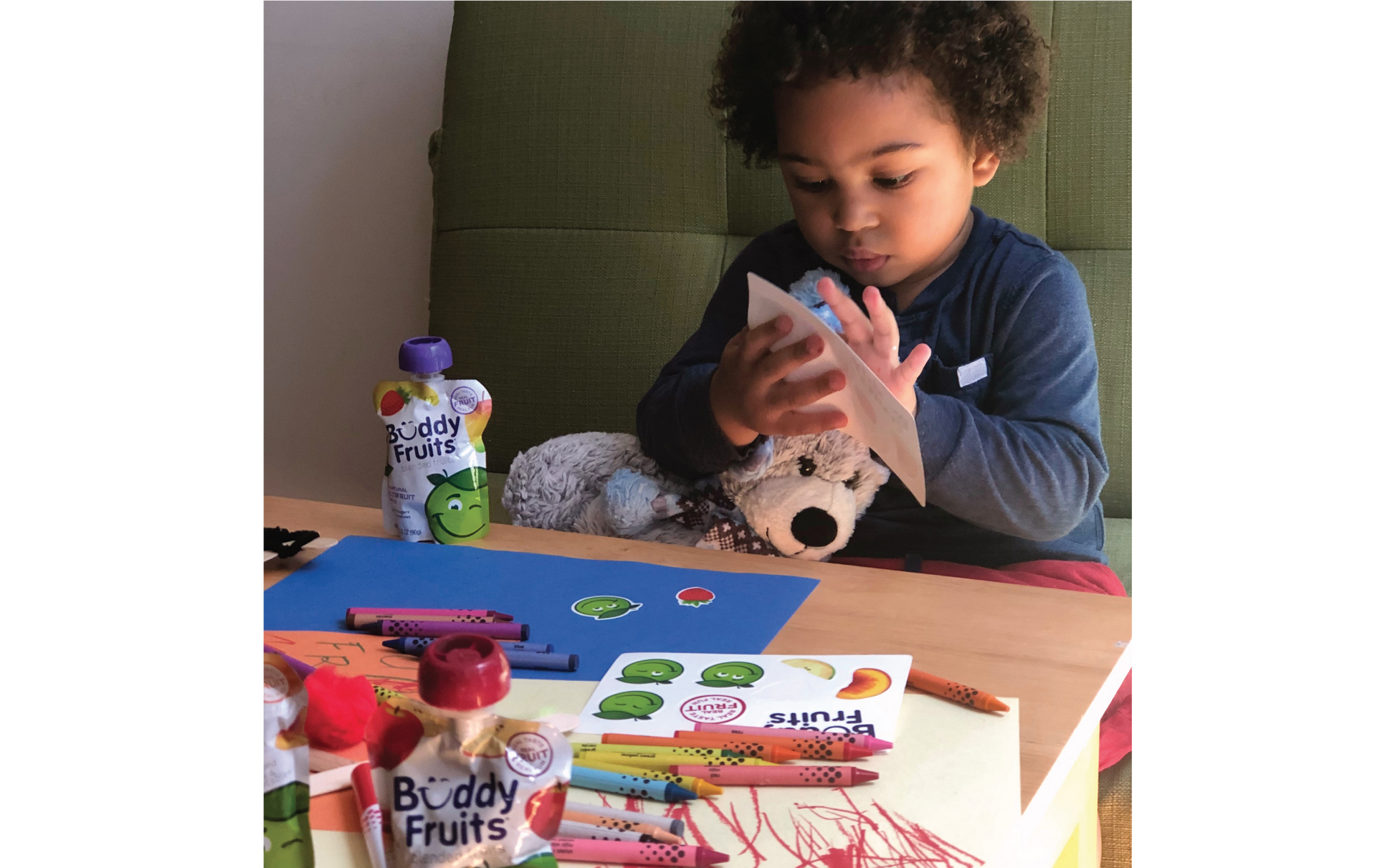 A young boy enjoys arts and crafts time with the explosive flavors of Buddy Fruits Multifruit & Apple fruit pouch.