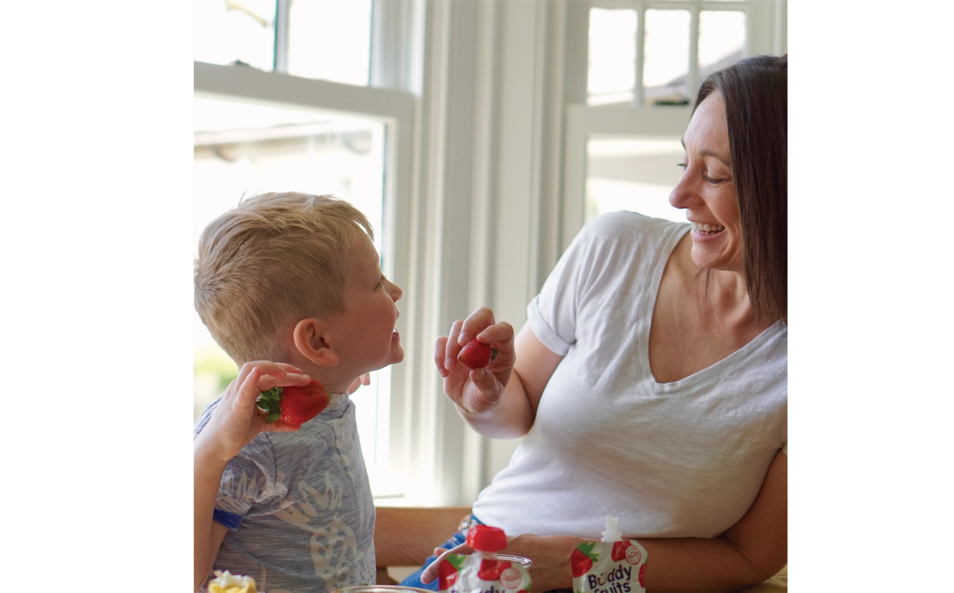 Mother and son playfully enjoy the delicious taste of Buddy Fruits Strawberry & Apple fruit pouch.