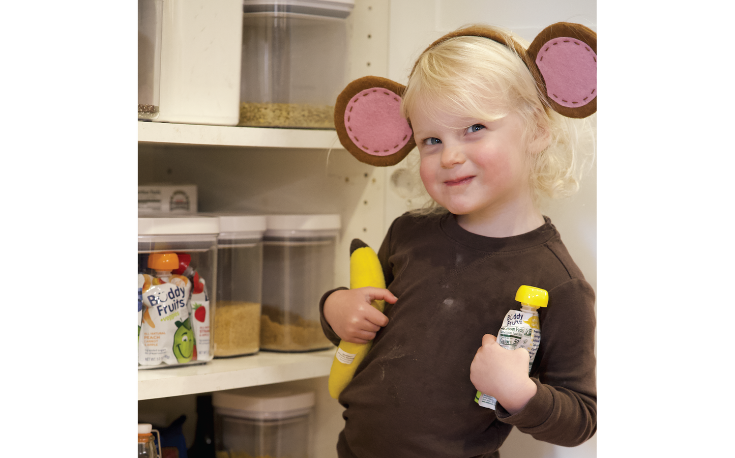 Young Buddy Fruits fan in a monkey costume sneaks into pantry to enjoy a Buddy Fruits Banana & Apple fruit pouch.